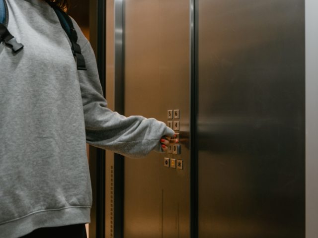 dziewczyna stoi przy windzie i wciska guzik windy