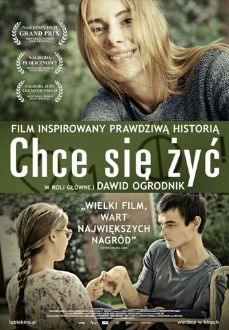 Plakat filmu pt. Chce się żyć. Tytul jest na środku. Powyżej twarz szeroko uśmiechniętej dziewczyny z rozwianymi, długimi włosami, okalającymi twarz. Poniżej napisy dziewczyna z warkoczem trzyma za palce chłopaka z mózgowym porażeniem, siedzącym na wózku