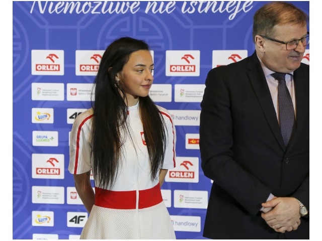 Biathlonistka Iweta Faron stoi obok Tomasza Maruszewskiegozastępcy prezesa PFRON na tle banera Polskiego Związku Paraolimpijskiego. 