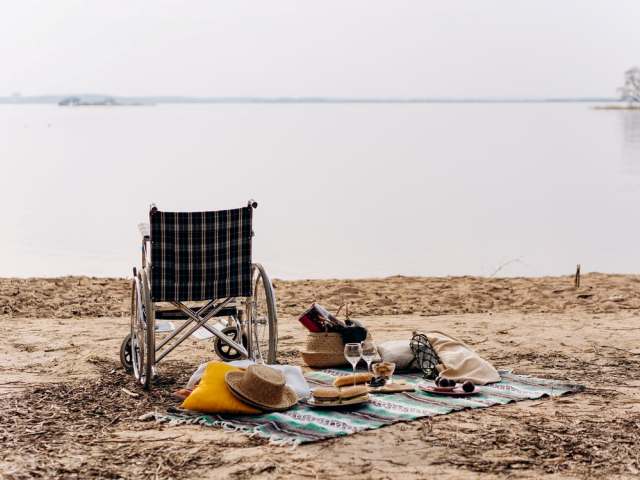 Wózek inwalidzki i rozłożony piknik nad rzeką.