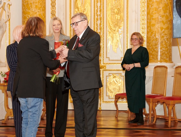 Stanisław Schubert, starszy mężczyzna w okularach, ubrany w garnitur odbiera statuetkę 