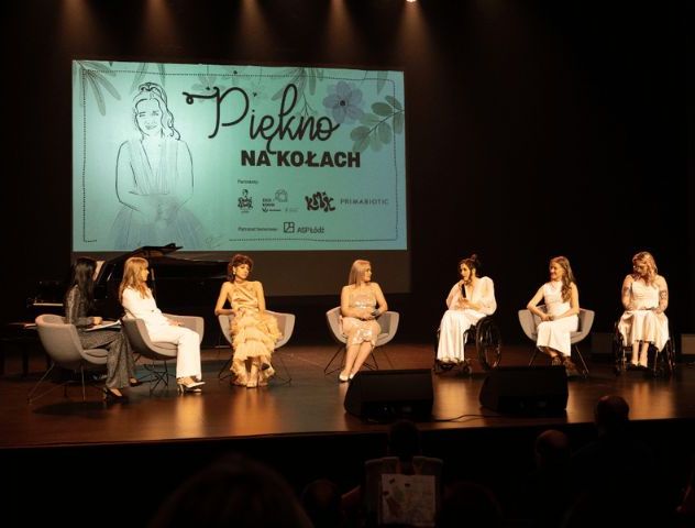 Kobiety podczas uczestniczenia w paneclu na scenie. Za nimi jest ekran z napisem "Piękno na kołach"