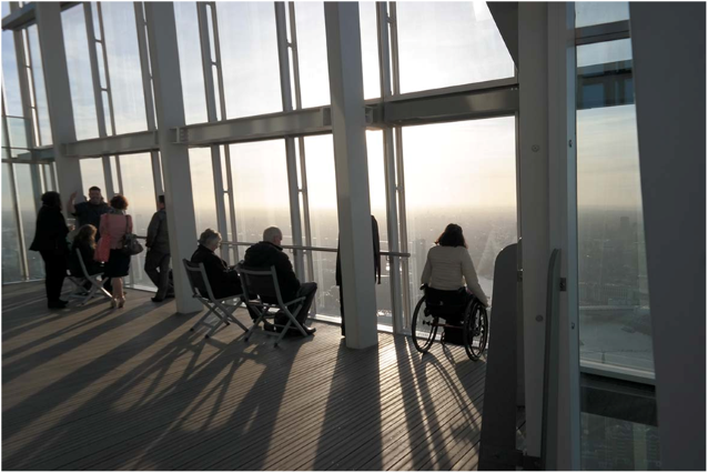 taras widokowy - część osób siedzi na krzesłach, część stoi, patrząc na panoramę Londynu