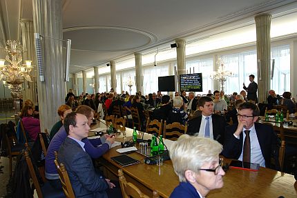 Uczestnicy konferencji siedzą za stołami słuchając wystąpienia w Sali Kolumnowej Sejmu