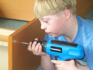 zdjęcie: chłopiec z zespołem Downa montujący półkę. Fot.: Wikipedia.